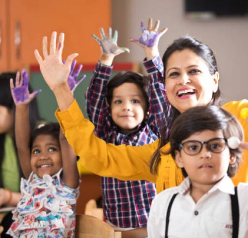 Teacher with preschool students having fun while finger painting at class