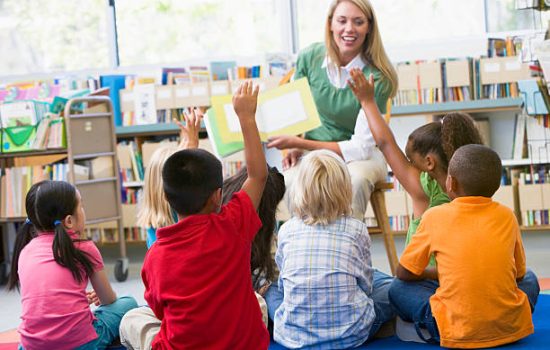 Kindergarten teacher reading to children in library